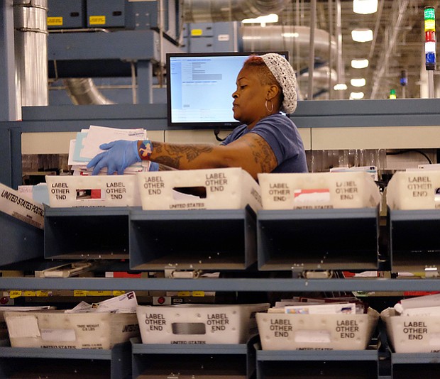 Taura James, above, sorts through the flood of letters and packages that have poured into the U.S. Postal Service’s Richmond Processing and Distribution Center in Sandston in Eastern Henrico County. Postal service officials showed off the plant Monday — the center’s busiest day that saw hundreds of employees handle  more than 2.4 million letters, cards and holiday packages. 