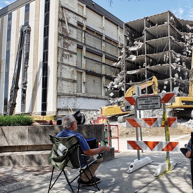 Spectators have a ringside seat as workers use powerful machines to demolish the parking deck of the vacant Richmond Plaza building at 7th and Cary streets in Downtown in August to make way for a 20-story office tower for Dominion Resources.