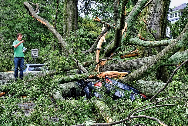 Brad Spangler takes a closer look at a car crushed under trees felled by a June storm that packed 70 mph winds, dropped 1.6 inches of rain and knocked out power to nearly 120,000 homes and businesses in Richmond and Henrico County. Location: Seminary and Claremont avenues in North Side.
