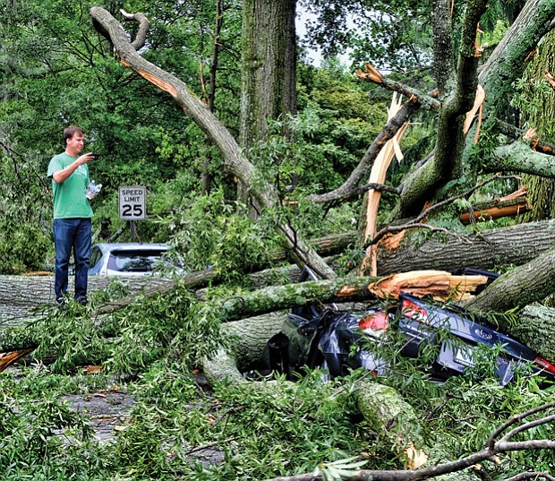 Brad Spangler takes a closer look at a car crushed under trees felled by a June storm that packed 70 mph winds, dropped 1.6 inches of rain and knocked out power to nearly 120,000 homes and businesses in Richmond and Henrico County. Location: Seminary and Claremont avenues in North Side.
