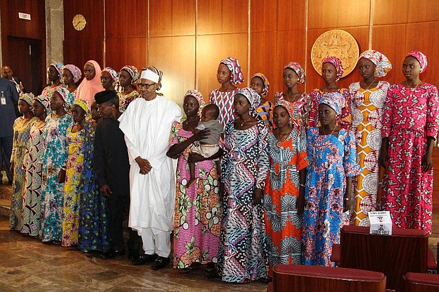 Nigerian President Muhammadu Buhari (C) poses on October 19, 2016 with the 21 Chibok girls who were released by Boko Haram last week, at the State House in Abuja, Nigeria. Speaking at the presidential villa in Nigeria’s capital of Abuja, Buhari addressed the girls and their families saying ‘we shall redouble efforts to ensure that we fulfil our pledge of bringing the remaining girls back home’. (AFP/Philip OJISUA)