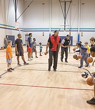 Former Virginia Commonwealth University Rams and NBA standouts Rolando Lamb, center left, and Calvin Duncan, center right, work with youngsters on dribbling skills during last week’s basketball camp in Midlothian.