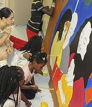 City Councilwoman Amanda Edwards painting with children on one of the youth mural