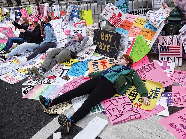 Marchers take a break and selfies surrounded by a plethora of protest signs left outside the new Trump International Hotel on Pennsylvania Avenue in Washington.