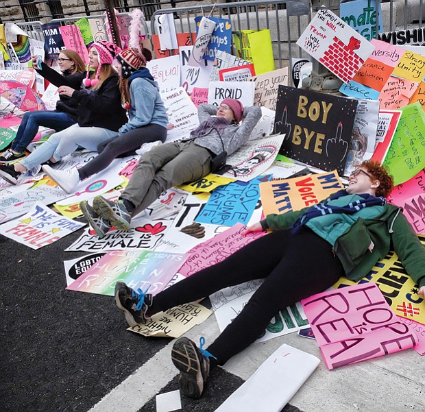 Marchers take a break and selfies surrounded by a plethora of protest signs left outside the new Trump International Hotel on Pennsylvania Avenue in Washington.