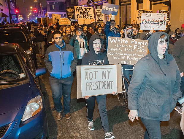 Several hundred protesters hold signs and chant as they march last Friday from Abner Clay Park in Richmond’s Jackson Ward in a demonstration by #disruptJ20.
