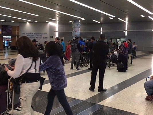 At Bush Airport, families waited Monday afternoon for relatives to arrive from overseas. It could take hours for them to …