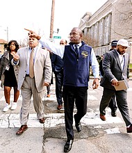 Checking the pulse of the city //
Richmond Mayor Levar M. Stoney, center, leads a group of about 40 people Wednesday during a tour of the Brookland Park Boulevard business corridor in North Side. Accompanied by City Council President Chris A. Hilbert, 3rd District, Mayor Stoney was shown buildings tagged with graffiti that need to be cleaned as well as Scott’s Funeral Home’s new chapel. The mayor also met business owners along the route, including including the proprietors of the renovated Two Pillars Tattoo and Sign Shop. Walking to his left is Richard A. Lambert Sr., president and owner of the funeral home. Saying he wants to be a “hands on, visible mayor,” Mayor Stoney plans to walk the Jefferson Davis Highway corridor in South Richmond next week with 8th District City Council member Reva M. Trammell.