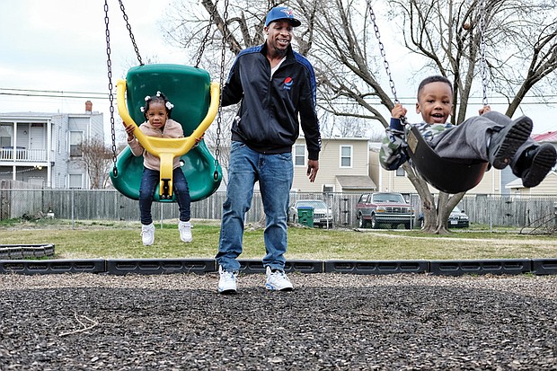 
Family fun //
Jamal Marshall and his children, Zuri, 2, left, and Jamal Jr., 4, take advantage of the springlike weather to enjoy family time on the swings at the George Mason Elementary School playground in Church Hill. Temperatures in Richmond are to soar into the 70s through Saturday.