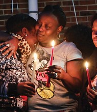 Victims mourned //
From left, LaTanya, China and Dequalla Walker join family, friends, neighbors and others at a candlelight vigil Monday evening to remember their sister, Shaquenda Walker, 24, and their mother, Deborah Walker, 55.