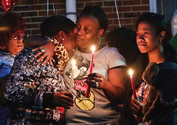 Victims mourned //
From left, LaTanya, China and Dequalla Walker join family, friends, neighbors and others at a candlelight vigil Monday evening to remember their sister, Shaquenda Walker, 24, and their mother, Deborah Walker, 55.