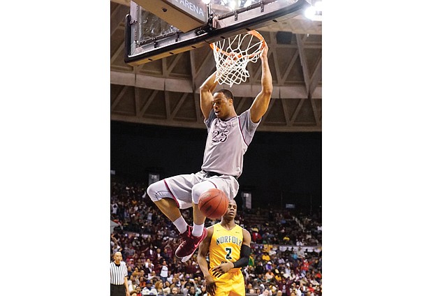 Kyle Benton of North Carolina Central University hangs from the rim after a slam dunk on Norfolk State University’s Zaynah Robinson in last Saturday’s championship game in the MEAC Tournament at the Norfolk Scope.