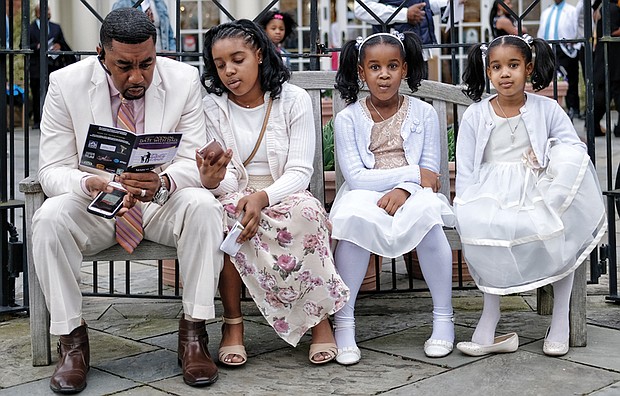 Freddie Royal takes a moment to peruse the activity schedule as he sits with his daughters, from left, Kyra, Amirah and Jada.