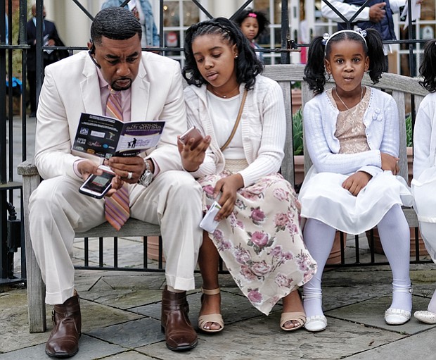 Freddie Royal takes a moment to peruse the activity schedule as he sits with his daughters, from left, Kyra, Amirah and Jada.