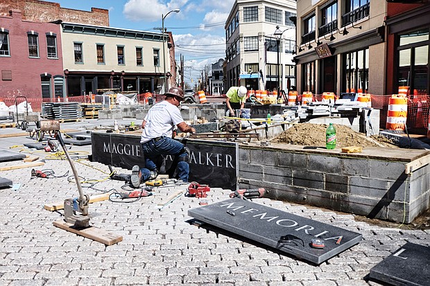 Cityscape // Wayne Floyd, left, and Jordan Wiles from Empire Granite work on the pedestal where the new statue of Richmond great Maggie L. Walker is to stand. The plaza at Broad and Adams streets is expected to be complete in four to six weeks. The bronze statue of Mrs. Walker “is finished,” sculptor Tony Mendez said Wednesday. It was completed two weeks ago, he said. He’s now awaiting instructions from the city about when it is to be delivered to the site. So far, City Hall has yet to announce a date for the dedication as officials work with the Mrs. Walker’s descendants on the timing. Mr. Mendez said there has been talk about holding the program on Saturday, July 15, Mrs. Walker’s birth date. This year would be the 153rd anniversary of the birth of the founder and president of the first bank to be chartered by an African-American woman. The total project cost: About $900,000.  