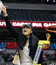 Dawn Staley, coach of the University of South Carolina women’s basketball team and a former University of Virginia basketball star, waves the freshly cut net to celebrate her team’s NCAA championship victory Sunday over Mississippi State University.