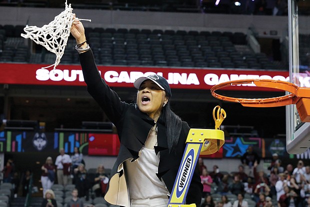 Dawn Staley, coach of the University of South Carolina women’s basketball team and a former University of Virginia basketball star, waves the freshly cut net to celebrate her team’s NCAA championship victory Sunday over Mississippi State University.