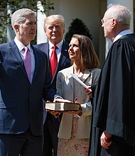 Justice Neil Gorsuch is sworn into the U.S. Supreme Court Monday by Justice Anthony Kennedy during a public ceremony in the White House Rose Garden. Justice Gorsuch’s wife, Marie Louise, holds the Bible, while President Trump observes.