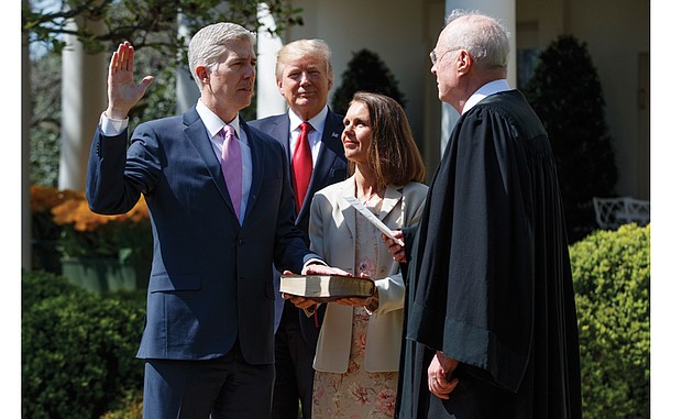 Justice Neil Gorsuch is sworn into the U.S. Supreme Court Monday by Justice Anthony Kennedy during a public ceremony in the White House Rose Garden. Justice Gorsuch’s wife, Marie Louise, holds the Bible, while President Trump observes.