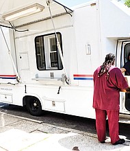 Post Office on Wheels // A customer takes care of business at the Post Office on Wheels that opened Monday outside the Church Hill Postal Station at 414 N. 25th St. The mobile center arrived after the building was shut down earlier that day to the dismay of residents.