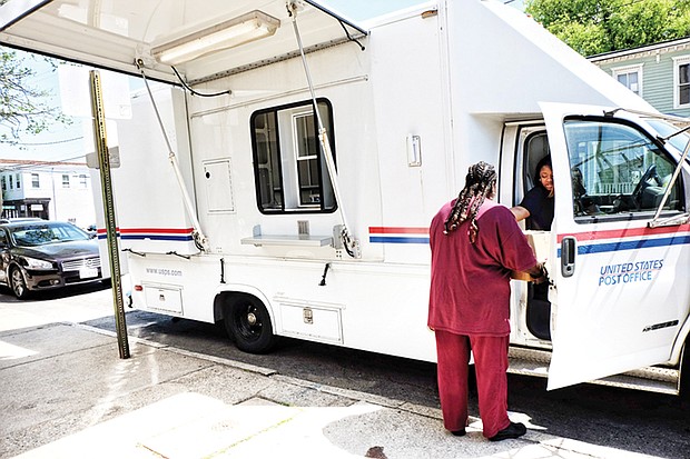 Post Office on Wheels // A customer takes care of business at the Post Office on Wheels that opened Monday outside the Church Hill Postal Station at 414 N. 25th St. The mobile center arrived after the building was shut down earlier that day to the dismay of residents.