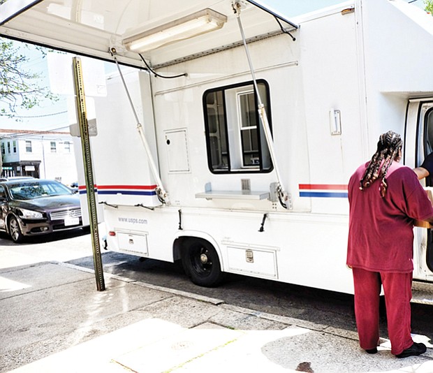 Post Office on Wheels // A customer takes care of business at the Post Office on Wheels that opened Monday outside the Church Hill Postal Station at 414 N. 25th St. The mobile center arrived after the building was shut down earlier that day to the dismay of residents.