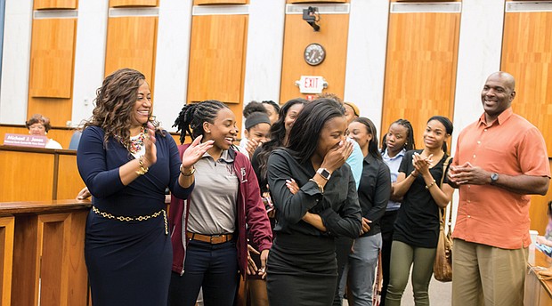 Honoring hometown champions  //
Virginia Union University basketball standout Ashley Smith, center, reacts to laudatory comments made by Richmond City Council President Chris A. Hilbert during Monday night’s City Council meeting. Ms. Smith, her teammates with the Lady Panthers and Coach AnnMarie Gilbert, left, were recognized by Mayor Levar M. Stoney and City Council for their championship showing in this year’s NCAA Division II Tournament. The Elite Eight team lost in the tournament final to Ashland University of Ohio. During the tournament, Dominion Energy lighted up its Downtown building with a message of support for the Lady Panthers. Mr. Hilbert said Monday the team lighted up the hearts of all Richmonders with its championship skill, poise and spirit. Ms. Smith scored 28 points in the team’s semifinal victory over California Baptist University, a feat Mr. Hilbert said he could never achieve, evoking laughter from the team.   