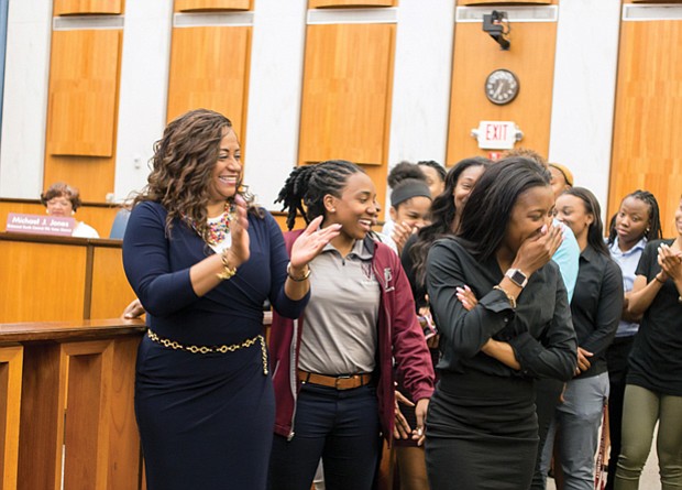 Honoring hometown champions  //
Virginia Union University basketball standout Ashley Smith, center, reacts to laudatory comments made by Richmond City Council President Chris A. Hilbert during Monday night’s City Council meeting. Ms. Smith, her teammates with the Lady Panthers and Coach AnnMarie Gilbert, left, were recognized by Mayor Levar M. Stoney and City Council for their championship showing in this year’s NCAA Division II Tournament. The Elite Eight team lost in the tournament final to Ashland University of Ohio. During the tournament, Dominion Energy lighted up its Downtown building with a message of support for the Lady Panthers. Mr. Hilbert said Monday the team lighted up the hearts of all Richmonders with its championship skill, poise and spirit. Ms. Smith scored 28 points in the team’s semifinal victory over California Baptist University, a feat Mr. Hilbert said he could never achieve, evoking laughter from the team.   