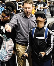 Yuan Canesius of Elkhardt-Thompson Middle School is guided by Alan Todd of Barton Malow in using a virtual reality headset, Oculus Rift, to play basketball. 
