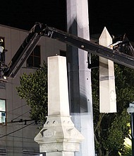 Workers dismantle the 35-foot granite Liberty Place monument Monday on Canal Street in New Orleans. The statue, which commemorates a white supremacist uprising in 1874, is being removed along with three others honoring Confederates.