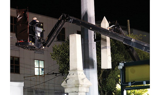 Workers dismantle the 35-foot granite Liberty Place monument Monday on Canal Street in New Orleans. The statue, which commemorates a white supremacist uprising in 1874, is being removed along with three others honoring Confederates.