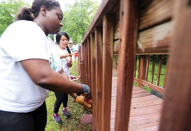 North Side spruces up //
Volunteers Erica Greene, left, and Sherita Sin brush stain on the ramp leading to a Highland Park home during Rebuilding Together Richmond’s blitz last Saturday to help repair and upgrade homes for elderly and low-income residents. Formerly known as Christmas in April, the daylong effort by the nonprofit organization drew nearly 1,000 volunteers to work on 39 homes in North Side as part of National Rebuilding Day and Affordable Housing Awareness Week. In its 25 years of helping to upgrade housing, Rebuilding Together Richmond has mobilized more than 25,000 volunteers who donated more than 200,000 hours to improve 1,300 homes. The organization values the work at $12 million. 