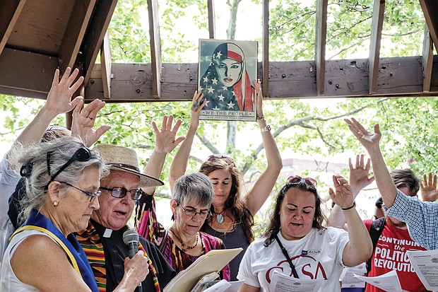 May Day protests in Richmond //  At left, Kim Bobo, left, and the Rev. Jack Posiadlo of Sacred Heart Catholic Church in South Richmond bless participants in the National Day Without Immigrants, timed to coincide with May Day observances on Monday, May 1. Location: Abner Clay Park in Jackson Ward. Similar events were held across the country to support immigrants and protest President Trump’s aggressive deportation policies. At right, boisterous protesters march on City Hall on Monday evening to urge the ouster of federal immigration agents and voice other concerns about federal and state policies.
