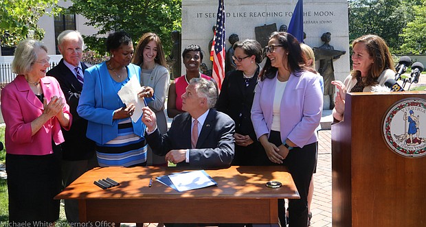 Making history //
Gov. Terry McAuliffe gives Richmond Delegate Delores L. McQuinn his pen Wednesday after signing a history-making bill into law that she patroned through the General Assembly. The new law ensures that 19th-century graves, monuments and markers of African-Americans will get the same state support as the burial sites of Confederate soldiers who fought to keep them enslaved. The governor also signed a second bill Richmond Delegate Jennifer L. McClellan ushered through the legislature that clears the way for the Virginia Foundation for the Humanities to preserve and tell the story of sites in the state linked to enslaved people.  Among those taking part in the signing ceremony are, from left, Richmond Delegate Betsy B. Carr; Powhatan Delegate R. Lee Ware; Delegate McQuinn; Fairfax Delegate Eileen Filler-Corn; Petersburg Delegate Lashrecse D. Aird; Delegate McClellan; Virginia Outdoor Foundation Executive Director Brett Glymph; state Secretary of Natural Resources Molly Ward, hidden; and First Lady Dorothy McAuliffe.  The ceremony took place in front of the Civil Rights Monument in Capitol Square.