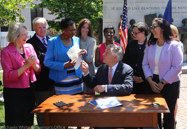 Making history //
Gov. Terry McAuliffe gives Richmond Delegate Delores L. McQuinn his pen Wednesday after signing a history-making bill into law that she patroned through the General Assembly. The new law ensures that 19th-century graves, monuments and markers of African-Americans will get the same state support as the burial sites of Confederate soldiers who fought to keep them enslaved. The governor also signed a second bill Richmond Delegate Jennifer L. McClellan ushered through the legislature that clears the way for the Virginia Foundation for the Humanities to preserve and tell the story of sites in the state linked to enslaved people.  Among those taking part in the signing ceremony are, from left, Richmond Delegate Betsy B. Carr; Powhatan Delegate R. Lee Ware; Delegate McQuinn; Fairfax Delegate Eileen Filler-Corn; Petersburg Delegate Lashrecse D. Aird; Delegate McClellan; Virginia Outdoor Foundation Executive Director Brett Glymph; state Secretary of Natural Resources Molly Ward, hidden; and First Lady Dorothy McAuliffe.  The ceremony took place in front of the Civil Rights Monument in Capitol Square.