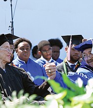 Retired NASA mathematician and pioneer Katherine G. Johnson, 98, gets a laudatory handshake from Hampton University President William R. Harvey after her videotaped commencement address Sunday to graduates and their families.