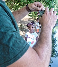 A family fishing affair //
Marley Worsham, 6, watches as the fish she caught at the 2017 Family Fishing Fair last Saturday in Byrd Park is taken off the hook by Tyler Twyford. Looking at Marley’s catch are her brothers, Luke, 5, and Jacob, 8. The event, held at Shields Lake, was sponsored by the Richmond Department of Parks, Recreation and Community Facilities. The youngsters attended with their parents, Shelley and Marco Worsham. 