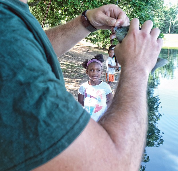 A family fishing affair //
Marley Worsham, 6, watches as the fish she caught at the 2017 Family Fishing Fair last Saturday in Byrd Park is taken off the hook by Tyler Twyford. Looking at Marley’s catch are her brothers, Luke, 5, and Jacob, 8. The event, held at Shields Lake, was sponsored by the Richmond Department of Parks, Recreation and Community Facilities. The youngsters attended with their parents, Shelley and Marco Worsham. 