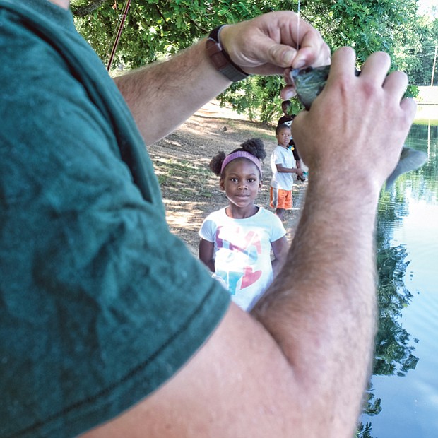 A family fishing affair //
Marley Worsham, 6, watches as the fish she caught at the 2017 Family Fishing Fair last Saturday in Byrd Park is taken off the hook by Tyler Twyford. Looking at Marley’s catch are her brothers, Luke, 5, and Jacob, 8. The event, held at Shields Lake, was sponsored by the Richmond Department of Parks, Recreation and Community Facilities. The youngsters attended with their parents, Shelley and Marco Worsham. 