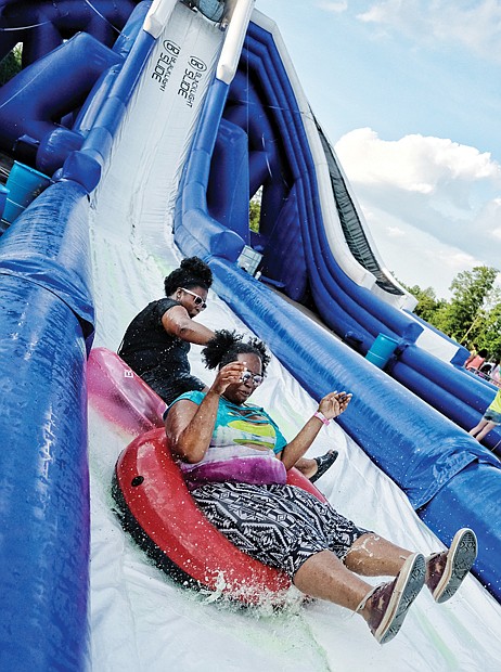 Fun in a different light // Sisters Jessica Fox and Toya Obasi ride down the slide before nightfall, when the blacklights’ effects are more visible. Hundreds of people turned out to enjoy the slide, music and fun on the warm evening. A portion of the event’s proceeds are to benefit the Children’s Miracle Network.