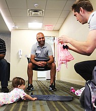 Jeff Duresky of Midlothan, right, shows off the outfit he will put on his daughter Sansa, 7 months, to dads-to-be Jarrod Loadholt, left, of Washington and Ricky Patel of Glen Allen. 