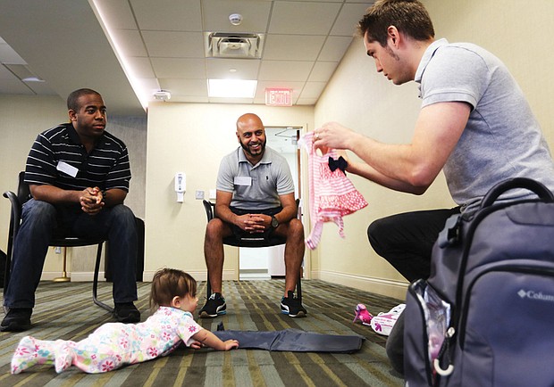 Jeff Duresky of Midlothan, right, shows off the outfit he will put on his daughter Sansa, 7 months, to dads-to-be Jarrod Loadholt, left, of Washington and Ricky Patel of Glen Allen. 