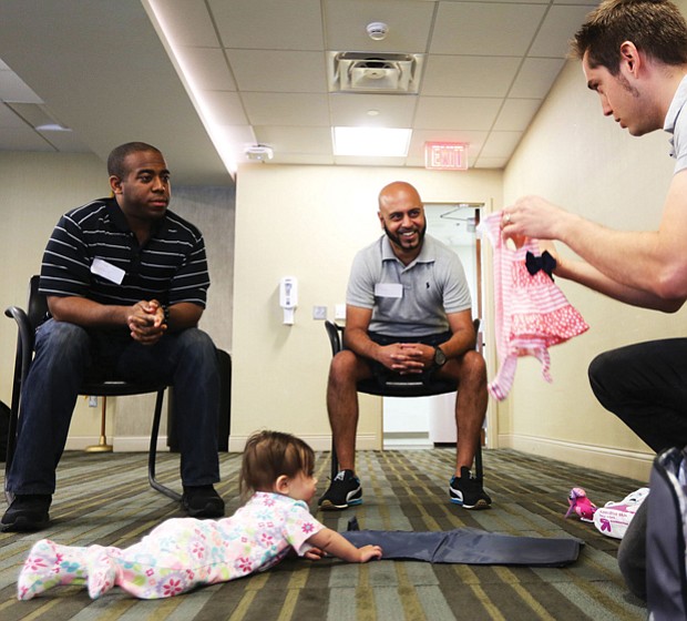 Jeff Duresky of Midlothan, right, shows off the outfit he will put on his daughter Sansa, 7 months, to dads-to-be Jarrod Loadholt, left, of Washington and Ricky Patel of Glen Allen. 