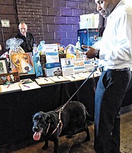 Pet Benefit // Kevin Epps peruses the silent action offerings with his black Labrador, Noell.