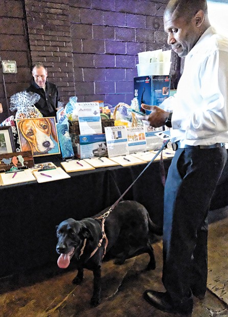 Pet Benefit // Kevin Epps peruses the silent action offerings with his black Labrador, Noell.