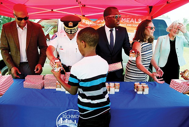 Jason Marshall, 9, receives a carton of milk and a boxed lunch from Richmond Police Chief Alfred Durham on Monday at the launch of the “No Kid Hungry Virginia” summer meals program. Location: The city’s new Southside Community Center at 6255 Old Warwick Road. Other officials serving meals include, from left: Richmond City Councilman Michael J. Jones, Mayor Levar M. Stoney, Virginia’s First Lady Dorothy McAuliffe and Richmond Delegate Betsy B. Carr. Anyone 18 and under is eligible for free breakfast and lunch through the U.S. Department of Agriculture-supported program without application or registration. Meals are available at 84 sites in Richmond, ranging from city recreation centers, schools and public housing offices to churches and day care centers. The goal is to ensure children receive nutritious meals when school is not in session. In past years, only 35 percent of city youths who receive free meals at school took advantage of the summer program. Mobile phones are making it simpler to find locations. Text the word FOOD or COMIDA to 877-877 and then enter a ZIP code to get information on nearby sites and times of service. Locations also are listed at www.fns.usda.gov/summerfoodrocks. 