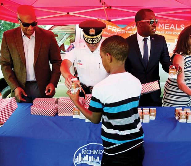 Jason Marshall, 9, receives a carton of milk and a boxed lunch from Richmond Police Chief Alfred Durham on Monday at the launch of the “No Kid Hungry Virginia” summer meals program. Location: The city’s new Southside Community Center at 6255 Old Warwick Road. Other officials serving meals include, from left: Richmond City Councilman Michael J. Jones, Mayor Levar M. Stoney, Virginia’s First Lady Dorothy McAuliffe and Richmond Delegate Betsy B. Carr. Anyone 18 and under is eligible for free breakfast and lunch through the U.S. Department of Agriculture-supported program without application or registration. Meals are available at 84 sites in Richmond, ranging from city recreation centers, schools and public housing offices to churches and day care centers. The goal is to ensure children receive nutritious meals when school is not in session. In past years, only 35 percent of city youths who receive free meals at school took advantage of the summer program. Mobile phones are making it simpler to find locations. Text the word FOOD or COMIDA to 877-877 and then enter a ZIP code to get information on nearby sites and times of service. Locations also are listed at www.fns.usda.gov/summerfoodrocks. 