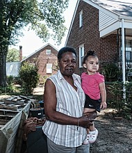 Charlene Harris holds her great-granddaughter, 14-month-old Kayla Love, outside her home, right, on Colorado Avenue in Randolph, where her family has lived since 1968. Despite surrounding properties being vacant and boarded up, Ms. Harris wanted to buy her home, but she’ll be moving in a few days.