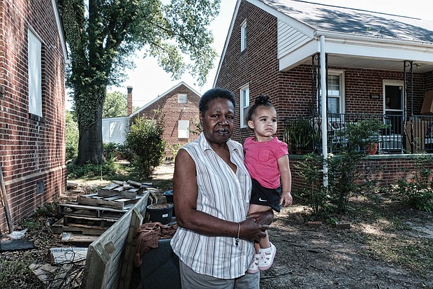 Charlene Harris holds her great-granddaughter, 14-month-old Kayla Love, outside her home, right, on Colorado Avenue in Randolph, where her family has lived since 1968. Despite surrounding properties being vacant and boarded up, Ms. Harris wanted to buy her home, but she’ll be moving in a few days.