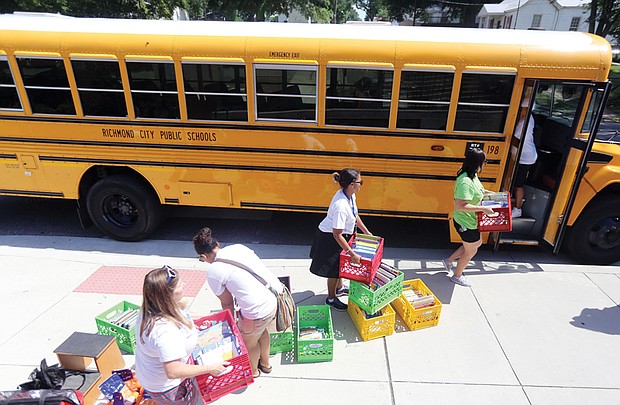 Teachers at Oak Grove-Bellemeade Elementary School load books onto the school’s R.E.A.D. Bus for its initial run Wednesday in neighborhoods in which the school’s students live. R.E.A.D. Buses from 20 of the city’s 24 elementary schools are part of the Reading Riders program to encourage students to read during the summer. 